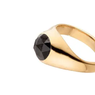 Angled shot of the black diamond ring highlighting its substantial recycled yellow gold band and minimalist yet bold silhouette.