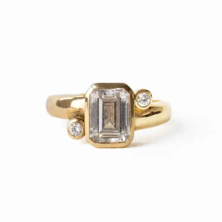 Front view of the Indigo Emerald Ring by June Rings, showcasing a 1.55ct emerald-cut center stone with .06ctw side stones, set in a 3.7mm domed band.