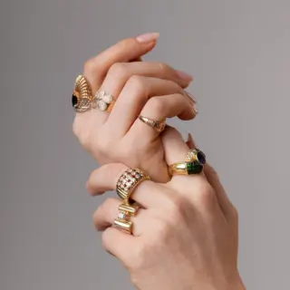 Styled flat-lay of Royal engagement ring in recycled 14K yellow gold, showcasing checkerboard layout of cabochon rubies and brilliant diamonds with vintage Art Deco flair