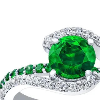 Close-up of tsavorite and diamond engagement ring showcasing the vivid green tsavorite garnet and intricate shared-prong diamond setting on a split band.