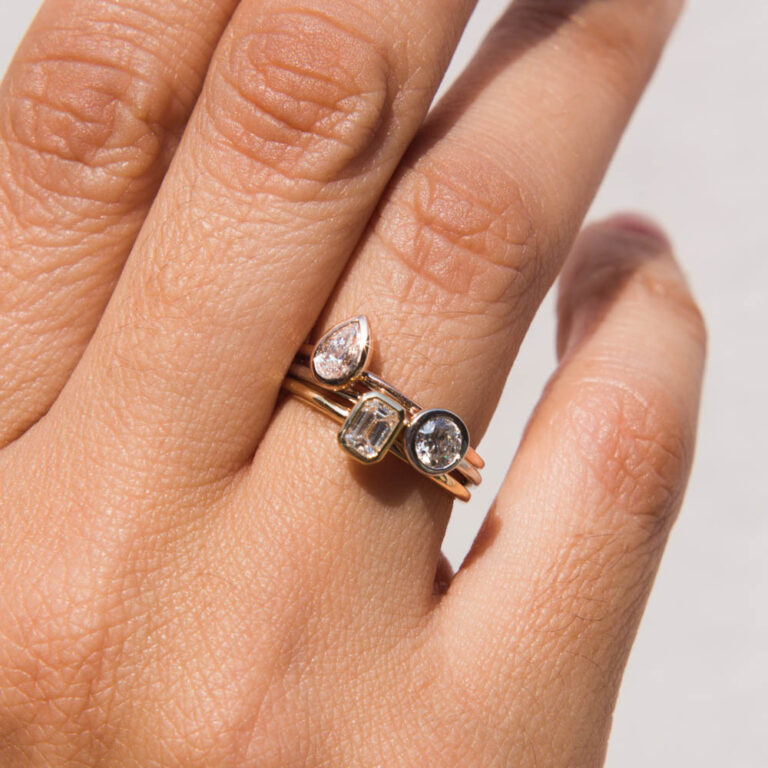 Close‑up of emerald‑cut 0.33 ct lab emerald bezel ring mounted on a slim, high‑polish white gold band