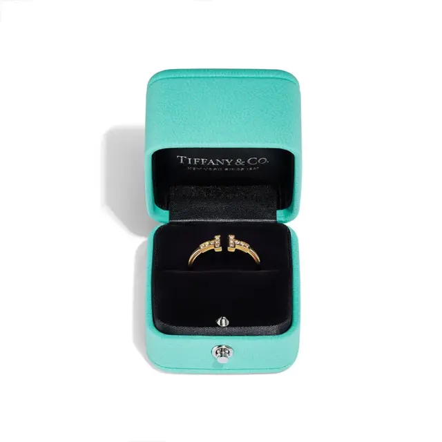 Lifestyle image of Tiffany T Diamond Wire Ring styled with other Tiffany rings, emphasizing its modern design in 18k yellow gold.
