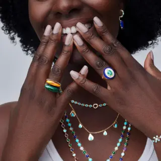 Model wearing 14K yellow gold Wise Monkeys Ring with diamond eyes, highlighting its whimsical design and symbolic mantra